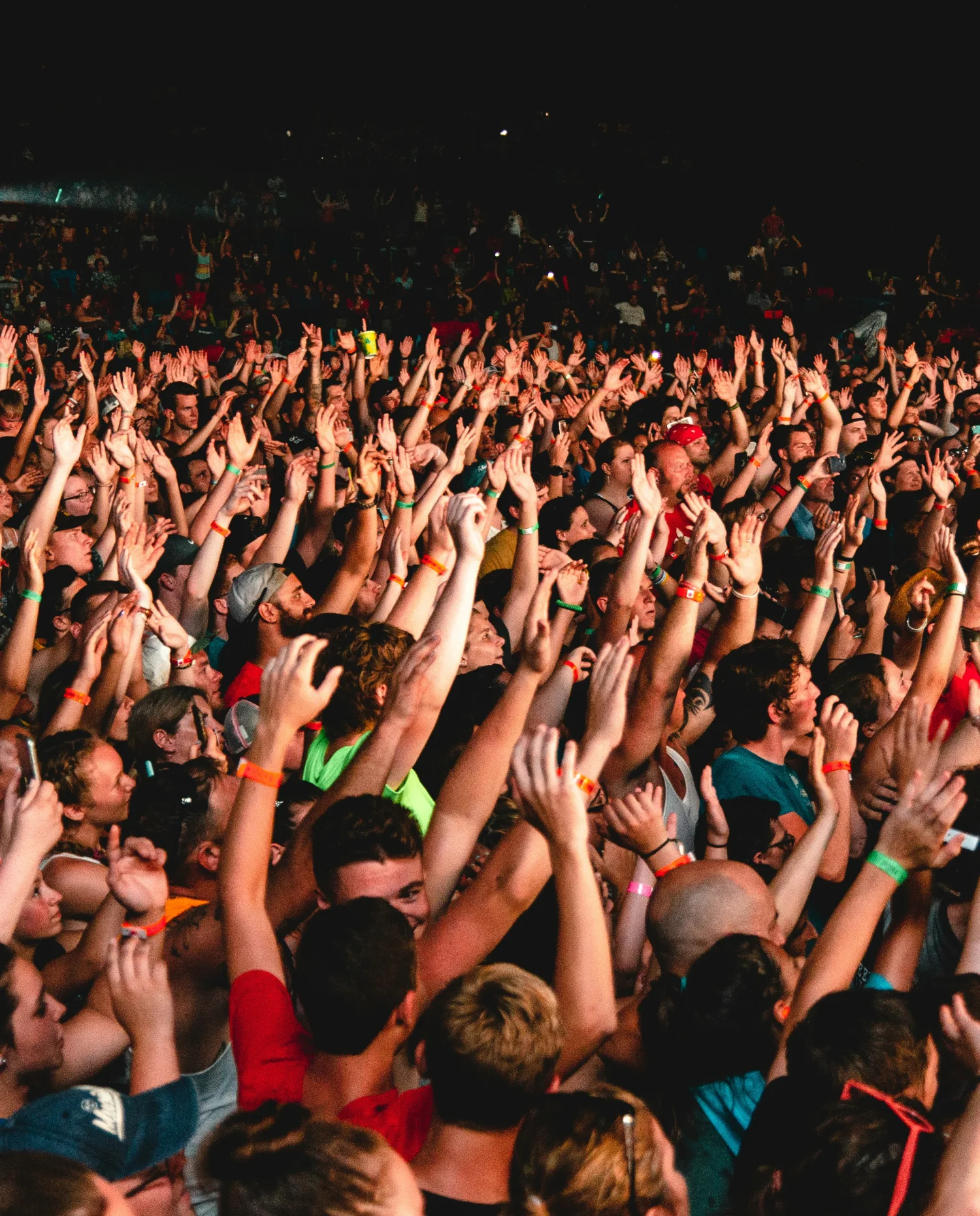 Dense festival crowd with raised hands at a monitored live event
